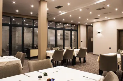 a restaurant with white tables and chairs and windows at Garni hotel FILIA in Nova Pazova