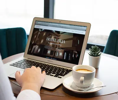 a person typing on a laptop with a cup of coffee at Garni hotel FILIA in Nova Pazova