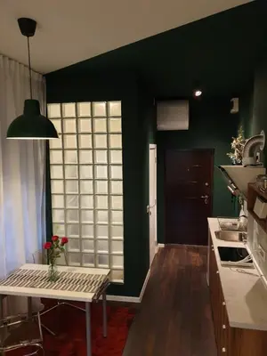 a kitchen with green walls and a table with a vase on it at Studio Apartment 