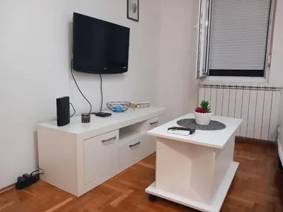 a white living room with a tv on a wall at BellaVista Apartmani in Stara Pazova