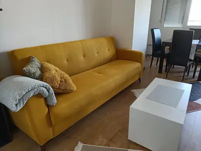 a yellow couch in a living room with a table at Apartment Dorcol in Belgrade