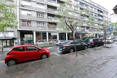 a red car parked on the side of a city street at Belgrade Center Apartment VI in Belgrade