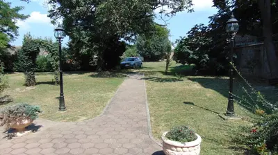 a walkway in a yard with two lights and a car at Rooms Milin Lagum in Irig