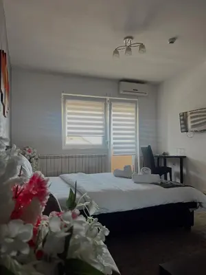 a bedroom with a bed and a window and flowers at Kengur Resort in Belgrade