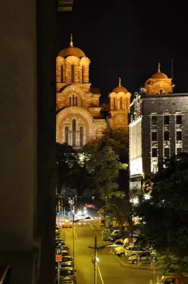 a large building with a clock tower at night at Apartments Legacy in Belgrade