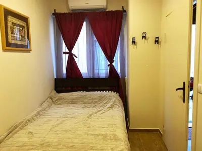 a bedroom with a bed with a red curtain and a window at Retro Mini Apartment in Zemun