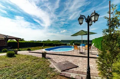 a pool with an umbrella and a street light at Villa Wisteria in Smederevo