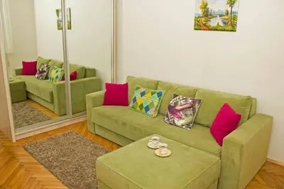 a living room with a green couch and a mirror at See U in Belgrade in Belgrade