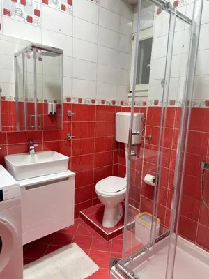 a red tiled bathroom with a toilet and a shower at Apartment Marsal in Belgrade