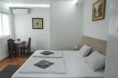 two beds in a room with a table and chairs at APARTMAN TEA in Belgrade