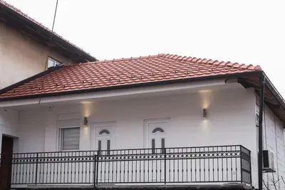 a white house with a balcony with a red roof at APARTMAN TEA in Belgrade