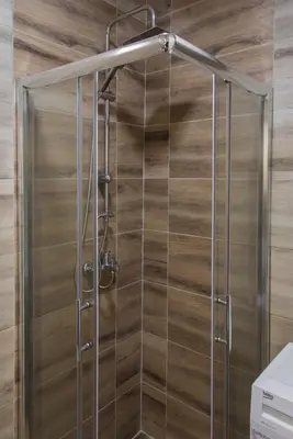 a shower in a bathroom with wooden walls at APARTMAN TEA in Belgrade