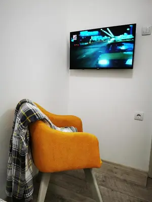 an orange chair sitting in front of a tv on a wall at Apartman ISKRA in Arandjelovac