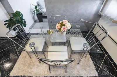 a glass table with chairs and a vase of flowers at Apartman ISKRA in Arandjelovac