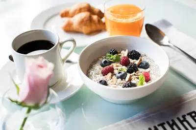a bowl of oatmeal with berries and a cup of coffee at Jump INN Hotel Belgrade in Belgrade