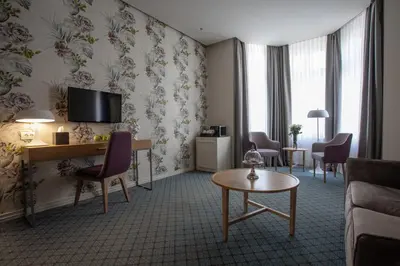 a hotel room with a living area with a couch and a table at Jump INN Hotel Belgrade in Belgrade