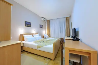 a bedroom with a bed and a desk with a television at Hotel Dragović Smederevo in Smederevo