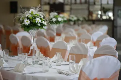a row of tables with white table cloth and a vase of flowers at Hotel Dragović Smederevo in Smederevo