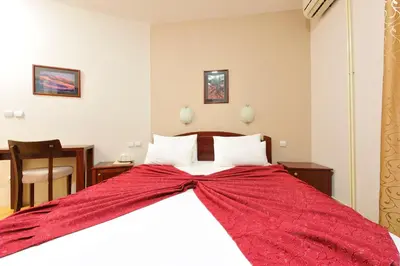 a bedroom with a large bed with a red blanket at Hotel Dragović Smederevo in Smederevo
