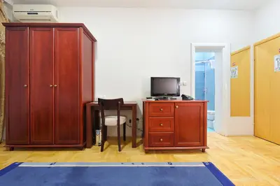 a room with a desk with a tv and a wooden cabinet at Hotel Dragović Smederevo in Smederevo