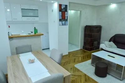 a living room with a dining table and a kitchen at Apartman Bazar in Smederevo