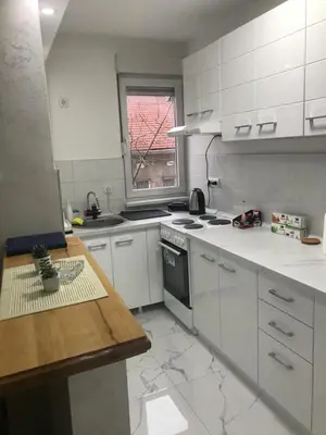 a kitchen with white cabinets and a table and a window at Apartman Bazar in Smederevo