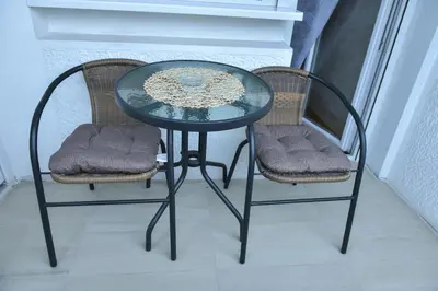 a glass table and two chairs sitting next to a window at Apartman Bazar in Smederevo