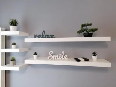 a white shelf with plants and a smile sign on a wall at FIT apartman in Belgrade