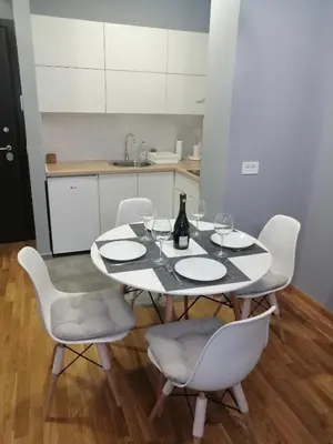 a white table with chairs and a bottle of wine at FIT apartman in Belgrade