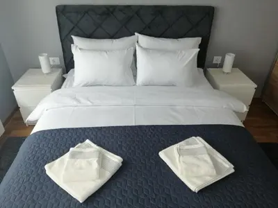 a bed with white towels on it with two night stands at FIT apartman in Belgrade