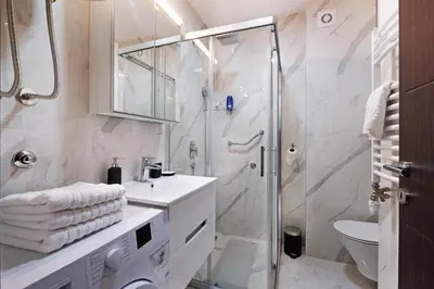 a white bathroom with a shower and a sink at Central SPA Galaxy Apartment in Belgrade