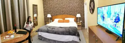 a woman in a hotel room with a bed and a tv at Contigo Apartments in Belgrade