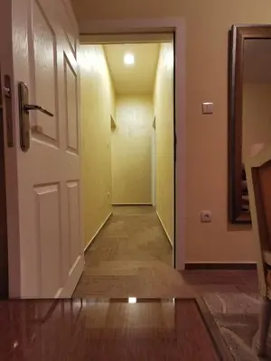 an empty hallway with a white door and wooden floors at Contigo Apartments in Belgrade