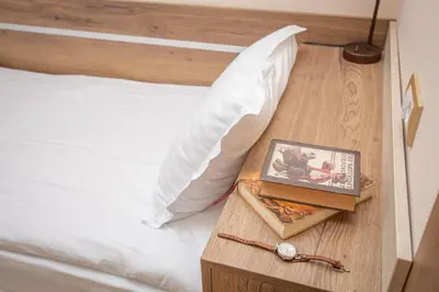a bed with a white pillow and a book on a table at HARIZMA 013 in Kovin