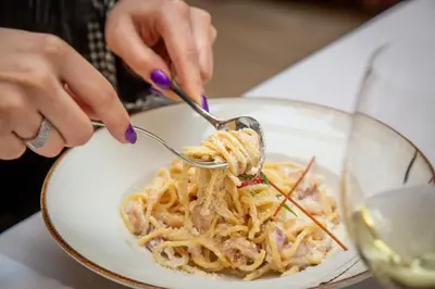 a person eating pasta on a plate with a fork and knife at HARIZMA 013 in Kovin
