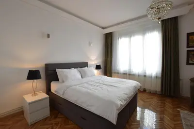 a bedroom with a large bed and a chandelier at Crown apartment - Your most comfortable stay in Belgrade