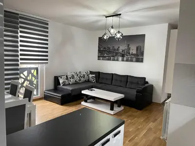 a living room with a black couch and a table at Royal Residence Apartmani 2 in Pančevo