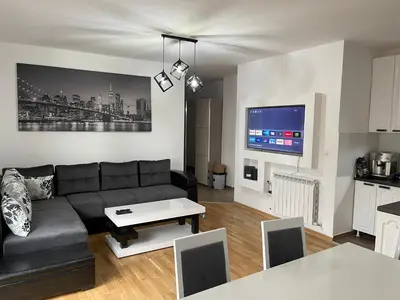 a living room with a black couch and a tv at Royal Residence Apartmani 2 in Pančevo
