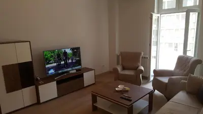 a living room with a television and a couch and chair at Beograd centar in Belgrade