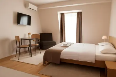 a bedroom with a bed and a table and a chair at Hotel Topcider in Belgrade