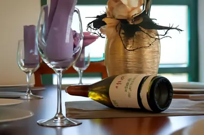 a bottle of wine sitting on a table with glasses at Hotel Topcider in Belgrade