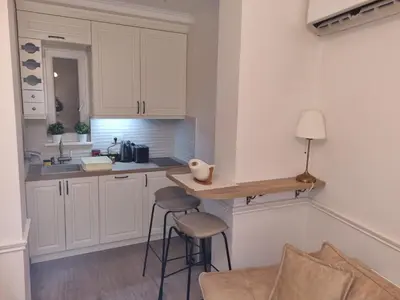 a kitchen with white cabinets and a counter with stools at Apartment Nusic residence in Belgrade