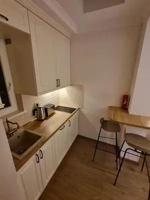 a kitchen with white cabinets and a sink and a table at Apartment Nusic residence in Belgrade