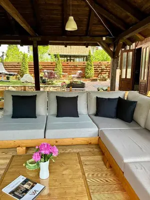 a couch on a patio with flowers on a table at Vila Aleksić in Smederevo