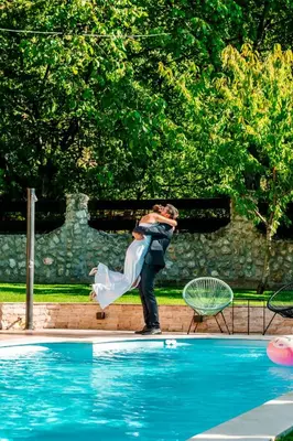 a man holding a bride in front of a pool at Vila Aleksić in Smederevo