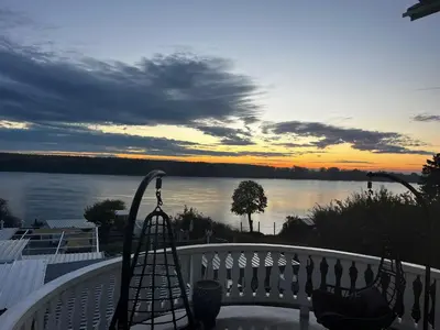 a view of the water from a balcony at sunset at Villa Danube , 25 min from Belgrade, 20 min Airport, Private Pool & Sauna in Novi Banovci