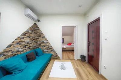 a living room with a blue couch and a brick wall at Vila Chess in Belgrade