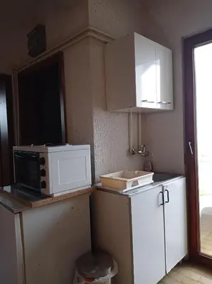 a kitchen with white cabinets and a microwave and a sink at APARTMAN U BUKOVICKOJ BANJI ARANDJELOVAC in Arandjelovac
