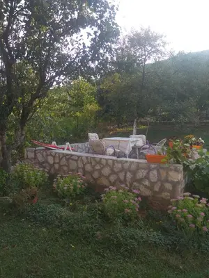 a stone bench with chairs in a garden at APARTMAN U BUKOVICKOJ BANJI ARANDJELOVAC in Arandjelovac