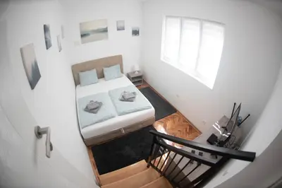 a small white bedroom with a bed and a window at APARTMAN TEA 2 in Belgrade